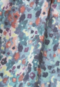 Textil med en ljusblå bakgrund och ett färgglatt, abstrakt mönster i olika former av röd, lila, gul och grönaktiga nyanser.