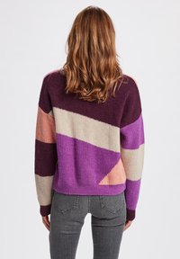 Maglione lavorato a maglia colorato con blocchi diagonali di viola, rosa e beige. Tessuto a costine, vestibilità ampia e maniche lunghe.
