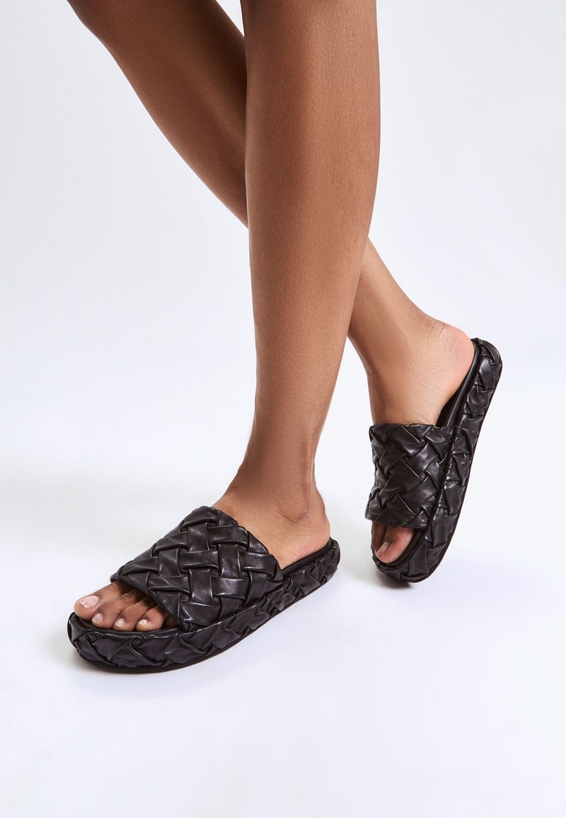 Sandali a fascia neri intrecciati con una parte superiore testurizzata e design open toe, dotati di una suola ammortizzata e forma chunky.
