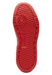 Czerwona podeszwa buta Reebok z diamentowym wzorem bieżnika, okrągłym punktem obrotowym i widoczną etykietą z oznaczeniem podeszwy niebrudzącej.