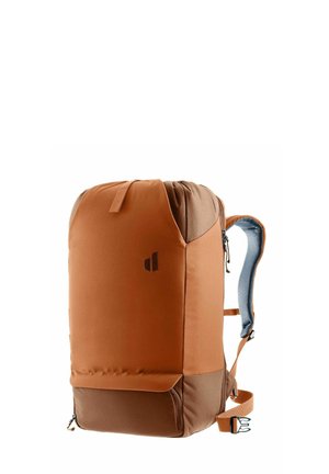 Sac à dos marron et beige avec des bretelles rembourrées, des compartiments zippés et un petit logo sur le devant, montré sur un fond blanc.