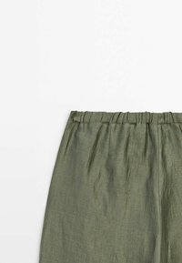 Pantalon en lin vert avec une ceinture élastique, présenté de la taille jusqu'au milieu de la cuisse sur fond blanc.