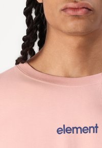 Lyserød t-shirt lavet af blødt bomuld, med et blåt "element" logo på fronten og en rund hals design.
