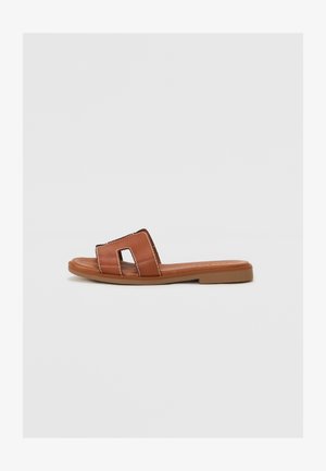 Sandal in pelle liscia di colore marrone con due cinturini a taglio, cuciture a contrasto, suola piatta e design minimalista.