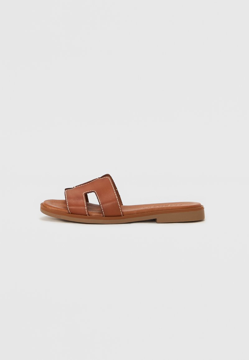 Brown slide sandal made of smooth leather featuring two cut-out straps, contrast stitching, flat sole with a minimalistic design.