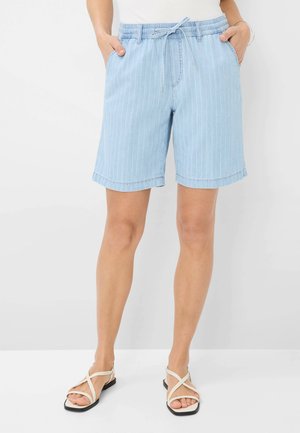 Lichtblauwe denim shorts met witte verticale strepen, elastische tailleband met trekkoord en omgeslagen mouwen. Gecombineerd met sandalen met bandjes.