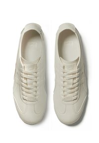 Beige sneakers med en slät, matt yta, som har en rund tå, snörningsdesign och subtila sömnadsdetaljer.