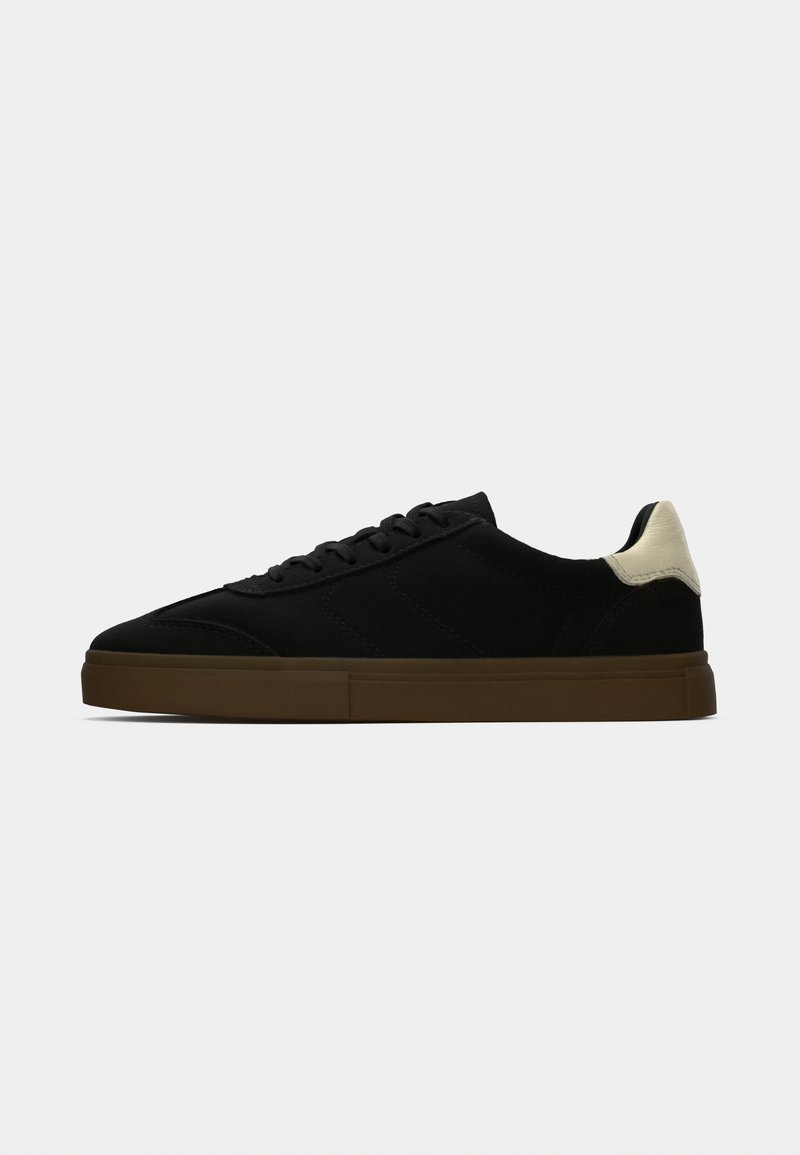 Adidași negri din suede cu un profil jos, având o talpă din cauciuc bej și un accent contrastant de crem la călcâi. Vârf rotund și design cu șireturi.