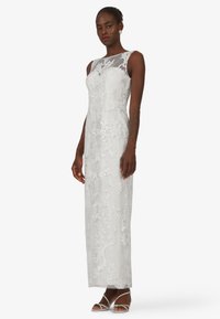 Langes, ärmelloses Kleid in Hellgrau mit floraler Stickerei und durchsichtigem Ausschnitt. Figurbetonte Silhouette, mit glatter Textur und bodenlanger Gestaltung.