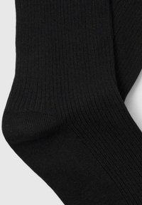 Črne rebraste nogavice z gladko teksturo, v zasnovi do gležnjev in ojačanom predelu prstov za trajnost.