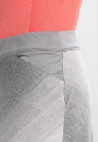 Leggings atléticos grises con un tejido liso y texturizado que presenta un degradado de color. La cinturilla es de un gris sólido en contraste.