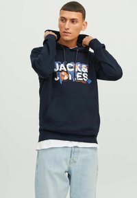 Sudadera de color azul marino hecha de algodón, con un estampado gráfico que incluye el texto "JACK & JONES". Cuenta con un bolsillo frontal y capucha con cordón.