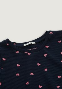 Marinblå ribbad väv med små rosa fjärilstryck och en rund halsringning med en innerskylt som säger "MADE WITH ECOLOGICAL."