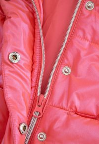 Wnętrze różowej, puszystej kurtki z suwakiem w kolorze srebrnym, metalowymi zatrzaskami i gładką satynową teksturą. Widoczne złożone, pikowane sekcje.