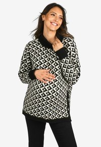 Sweter w czarno-białe wzory z dużym kołnierzem, teksturowanym splotem, długimi rękawami i bocznymi guzikami, zestawiony z czarnymi spodniami.