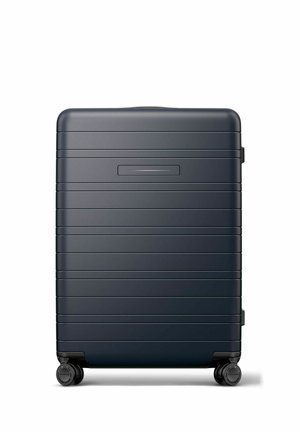 Dark blue hard-shell suitcase with horizontal ridges and four black spinner wheels on a white background.