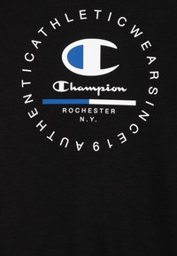 Čierna bavlnená mikina s okrúhlym bielym a modrým logom s textom "Champion", obklopená slovami "Athletic Wear Since 1919."