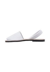 Sandalias blancas de material suave con un diseño de punta abierta, que cuentan con una correa en la parte trasera y una suela plana de goma negra.