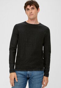 Zwarte long sleeve shirt van textuurstof, met een ronde hals en gestikte zoom, gecombineerd met blauwe spijkerbroek.
