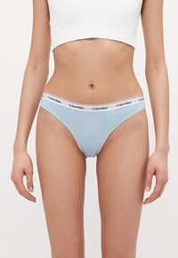 Lys blå bomullsunderbukser med en hvit kant som har "Calvin Klein"-logo. Glatt tekstur og lav midje-design.