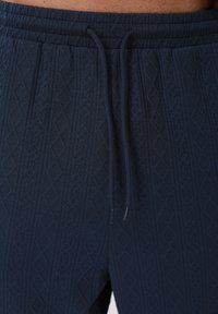 Pantalon bleu marine à taille élastique avec motif diamant texturé et cordons de serrage à l'avant.