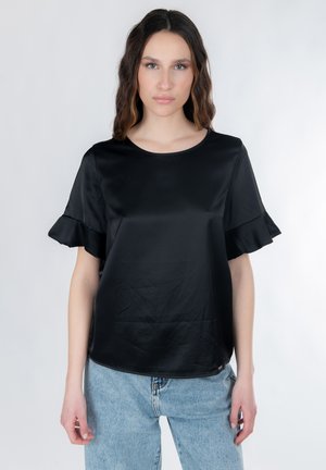 Sort satinbluse med korte flæseærmer, rund halsudskæring og en glat tekstur. Kombineret med lyseblå denimjeans.