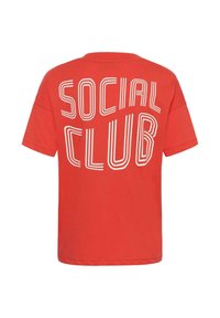 T-shirt rouge à manches courtes avec un grand texte blanc en contour "SOCIAL CLUB" au dos dans une police moderne et audacieuse.