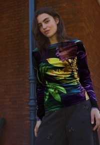 Satiinist ülemine osa, millel on värviline lilleline muster violetse, kollase ja rohelisega, pikad varrukad ja külgedel rühmitatud detailid.