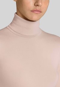 Maglia a collo alto aderente di colore rosa chiaro, con texture a righe, dal design senza cuciture, silhouette aderente, adatta per essere indossata a strati.