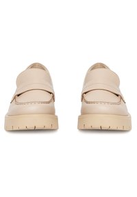 Béžové kožené mokasíny s okrúhlou špičkou a zvýšeným švom. Majú dizajn na obúvanie a textúrovanú gumovú podrážku s ryhami.