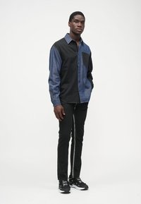 Koszula z guzikami w stylu color block w kolorze czarnym i granatowym, z kieszonką na piersi, w zestawie z czarnymi spodniami slim fit i sneakersami.