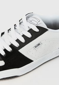 Black and white sneaker with a leather and suede upper, featuring white laces, a textured tongue, and a small "GLOBE" label on the side.