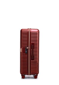 Harde koffer in metallic rood, met een geribbelde uitstraling, dubbele wielen, zijhandvat en een combinatie slot.