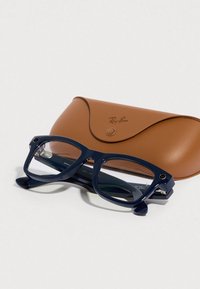 Gafas Ray-Ban con montura de plástico azul marino, forma rectangular, lentes transparentes, junto a un estuche de cuero marrón con cierre de broche.
