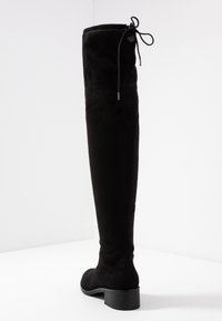Schwarze Overknee-Stiefel aus weichem, Samt-ähnlichem Material. Mit runder Spitze, niedrigem Blockabsatz und einer Schnürung oben.