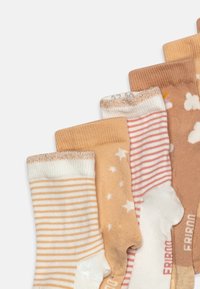 Sæt med syv sokker i nuancer af beige og creme, prydet med mønstre som striber, stjerner og skyer, samt teksturerede ribkanter og bløde materialer.