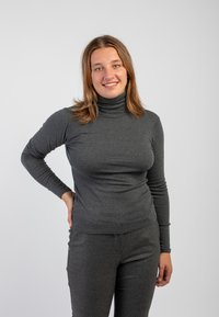 Maglione a collo alto grigio, aderente, con maniche lunghe, realizzato in un tessuto morbido e elastico. Abbinato a pantaloni grigi a vestibilità slim. Design semplice.