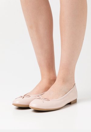 Lichtroze balletflat gemaakt van soepel leer, met een klein strikje aan de voorkant en een lage houten hak voor stabiliteit.