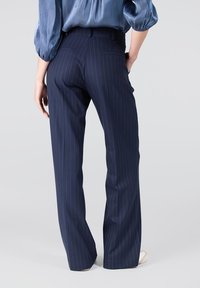 Marineblauwe pinstripe broeken met een Slim Fit, voorzien van een rechte pijpdesign, tailleband en achterzakken. Gladde stoftextuur.