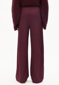 Weite Hosen in Burgunderrot, aus weichem Stoff. Elastischer Bund, voll Länge, mit glatter Textur und einfachen Nähdetails.