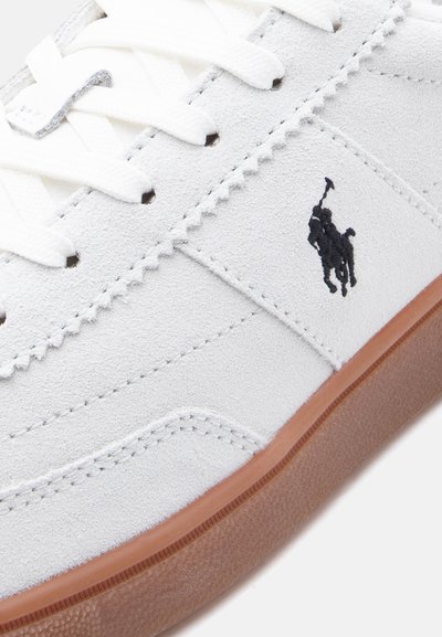 Λευκό αθλητικό παπούτσι από σουέτ με λευκά κορδόνια, καφέ καουτσούκ σόλα και μαύρο κεντημ ένο λογότυπο παίκτη πόλο στο πλαϊνό πάνελ.