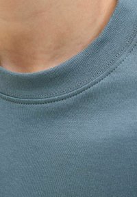T-shirt a maniche corte e collo rotondo in verde teal smorzato, realizzato in morbido cotone misto, con scollatura a costine e texture liscia.