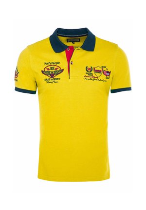 Geel poloshirt met marineblauwe kraag en mouwranden, rode binnenbies en race-thema geborduurde patches op borst en mouw.