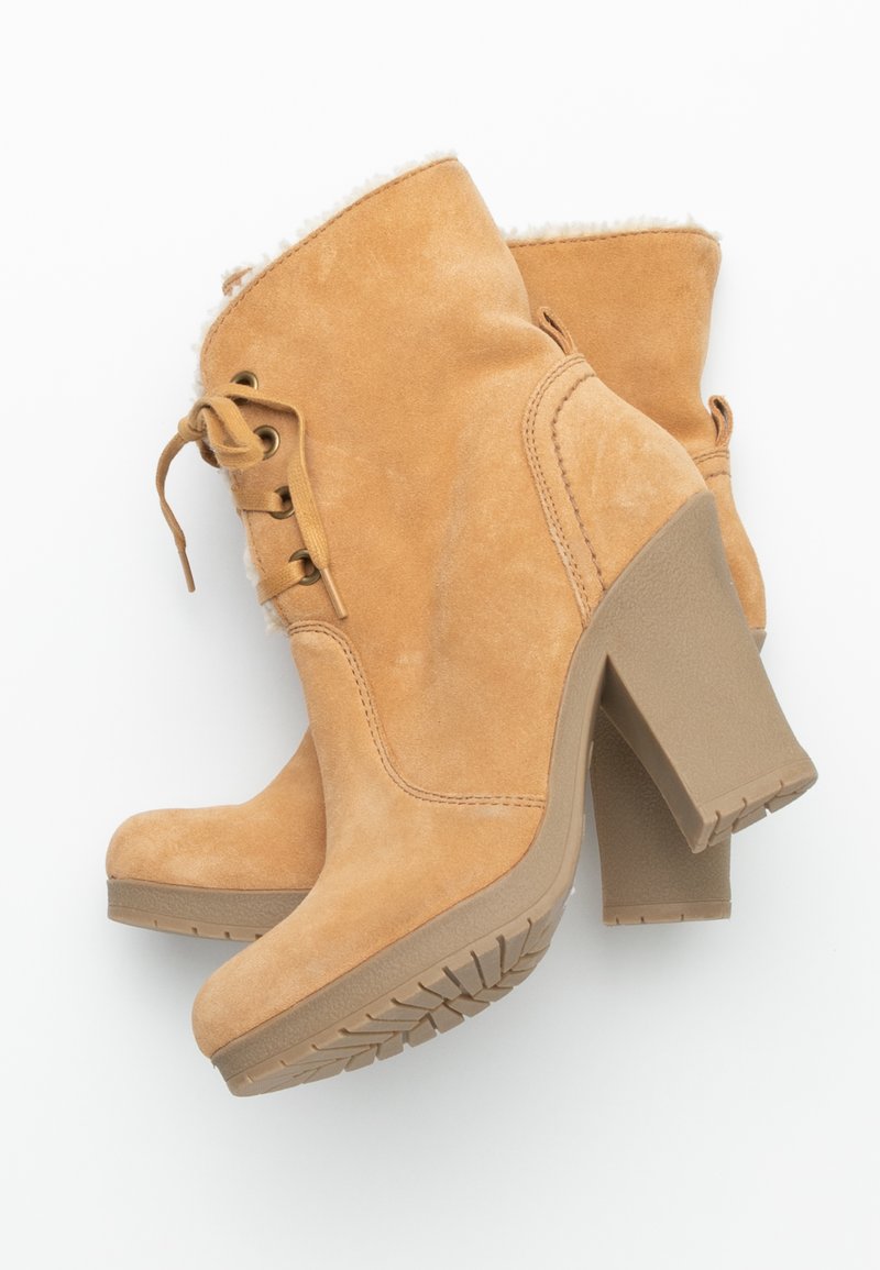 Tan suède enkellaarsjes met een nepvacht voering, vetersluiting en een brede hoge hak; gestructureerde rubberen zool voor grip.