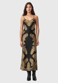 Sort satin kjole med guld paisley mønster, spaghetti stropper og et elegant, ankellangt design. Båret med knæhøje sorte støvler.