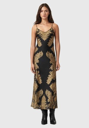 Sort satin kjole med guld paisley mønster, spaghetti stropper og et elegant, ankellangt design. Båret med knæhøje sorte støvler.