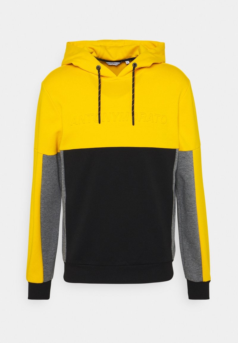 Sudadera con capucha bicolor en amarillo, negro y gris. Cuenta con capucha con cordón y logotipo en relieve en el pecho. Textura de tela suave.