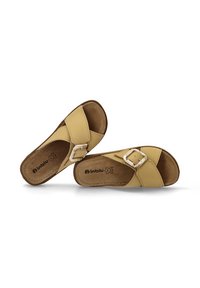 Sandalias de piel amarilla con diseño de tiras cruzadas y un acento de hebilla plateada. Forro interior suave con una suela texturizada marrón.