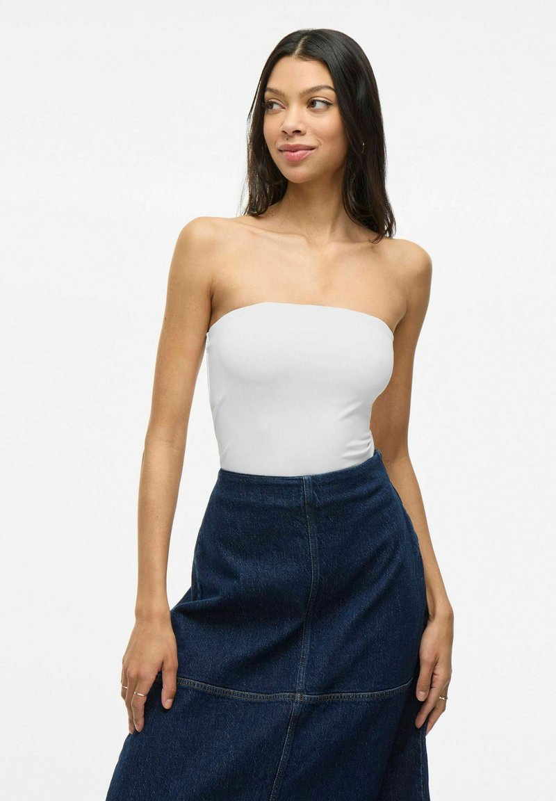 Body senza spalline bianco abbinato a una gonna di jeans blu scuro,con un design semplice, texture liscia e una silhouette aderente.