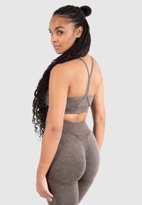 Conjunto de sujetador deportivo y leggings marrón con acabado texturizado, tirantes ajustables y diseño de cintura alta con acentos contorneados.